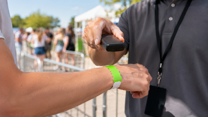 Staff scanning a Tyvek RFID wristband at an event entrance Staff scanning a Tyvek RFID wristband at an event entrance